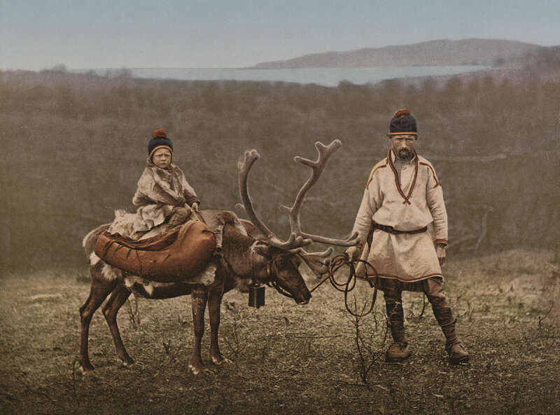Historical image of Sami man and child on reindeer