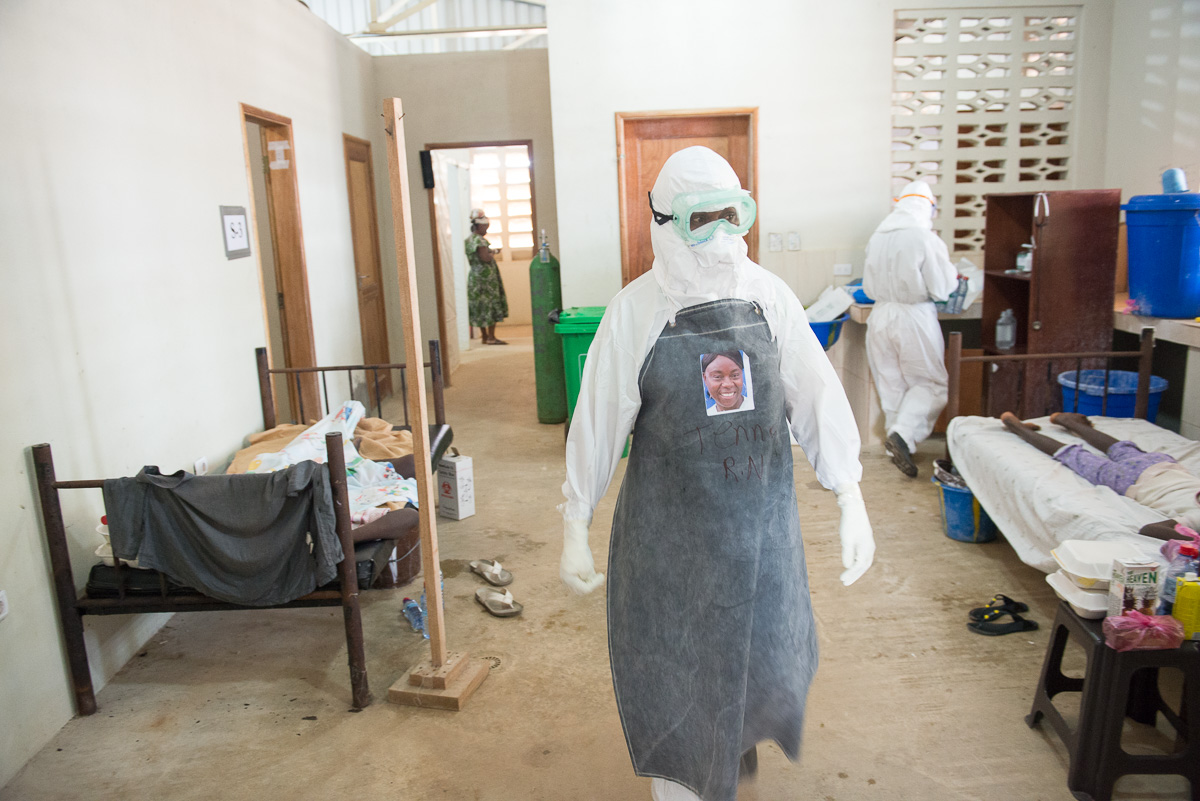 Photo of Health care workers make their rounds as they care for patients, including two new patients, in the ELWA II ETU (Ebola treatment unit), Monrovia, Liberia on Monday, March 9, 2015. Occidental College professor Mary Beth Heffernan’s PPE Portrait Project involves creating wearable portraits of the health care workers who must wear PPE (personal protective equipment) when working with patients. (Photo by Marc Campos, Occidental College Photographer), 2015.